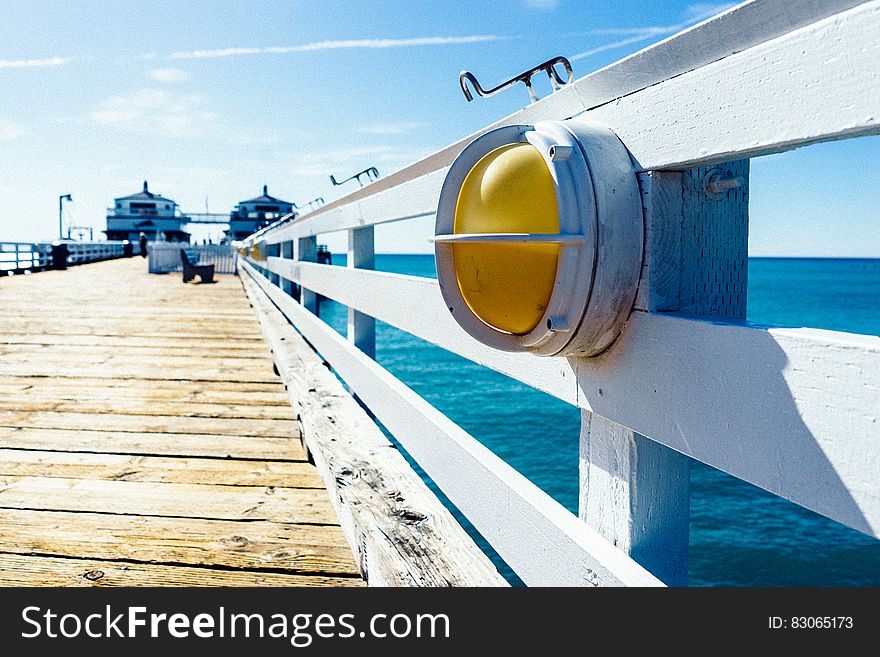 Close up of light on wooden rail of dock over blue waters. Close up of light on wooden rail of dock over blue waters.