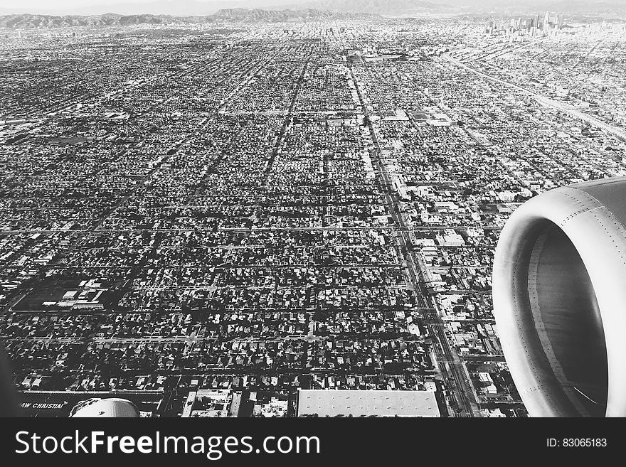 Black and white white of aircraft engine flying over sprawling cityscape. Black and white white of aircraft engine flying over sprawling cityscape.