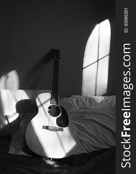 White Acoustic Guitar On Grey And White Textile