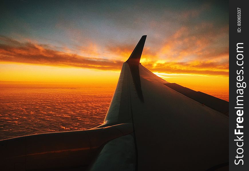 An airplane wing above open sea at sunset. An airplane wing above open sea at sunset.