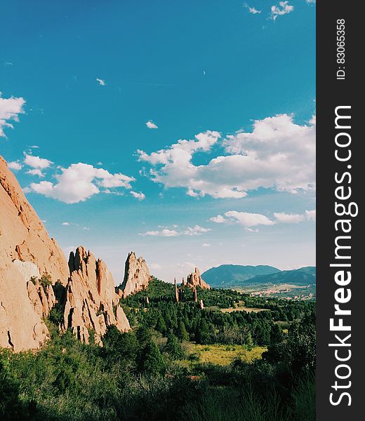 A landscape with steep mountains and green forests with blue skies. A landscape with steep mountains and green forests with blue skies.