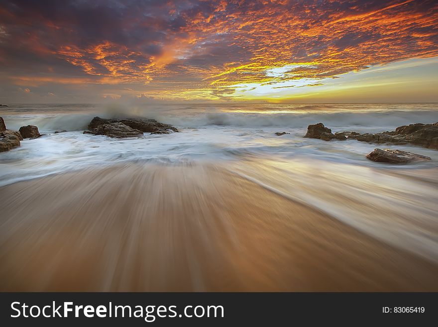 A long exposure of waves hitting the beach with sunset skies. A long exposure of waves hitting the beach with sunset skies.