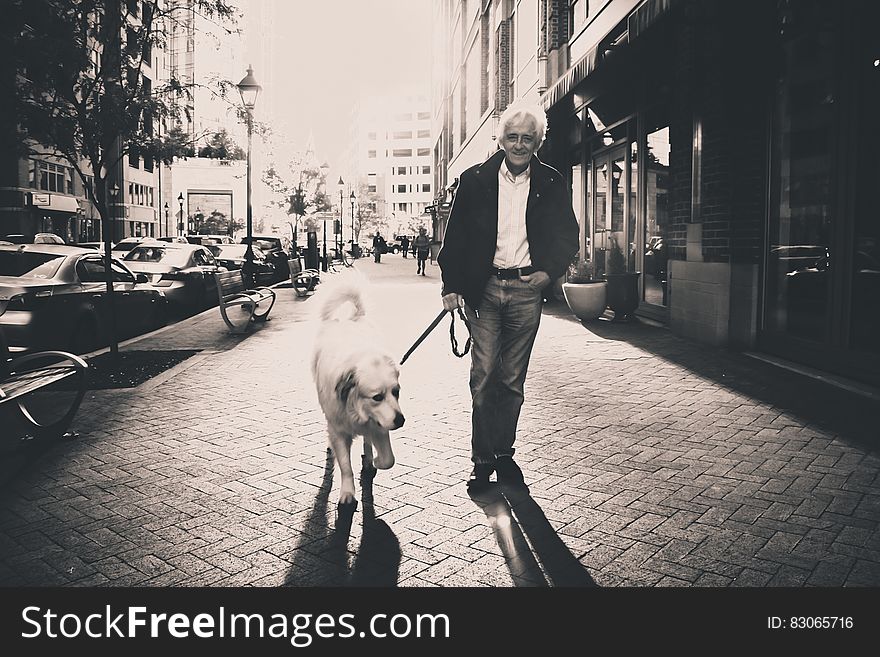 Portrait of man walking dog on city streets in black and white.