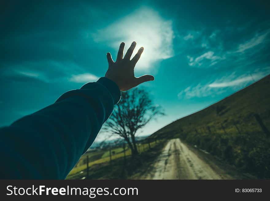 Person Raising Hand Towards Blue Sky during Daytime