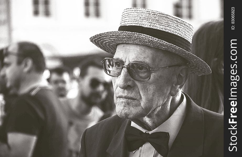 Man in Straw Hat Wearing Bow Tie With People