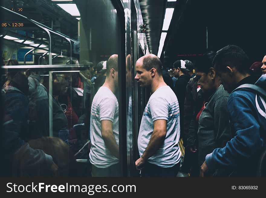 Man in Gray and Black Stripes Shirt in Train Station Looking Towards Train Door