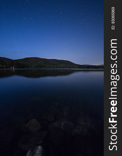 Lake View Under Clear Blue Night Sky During Night Time