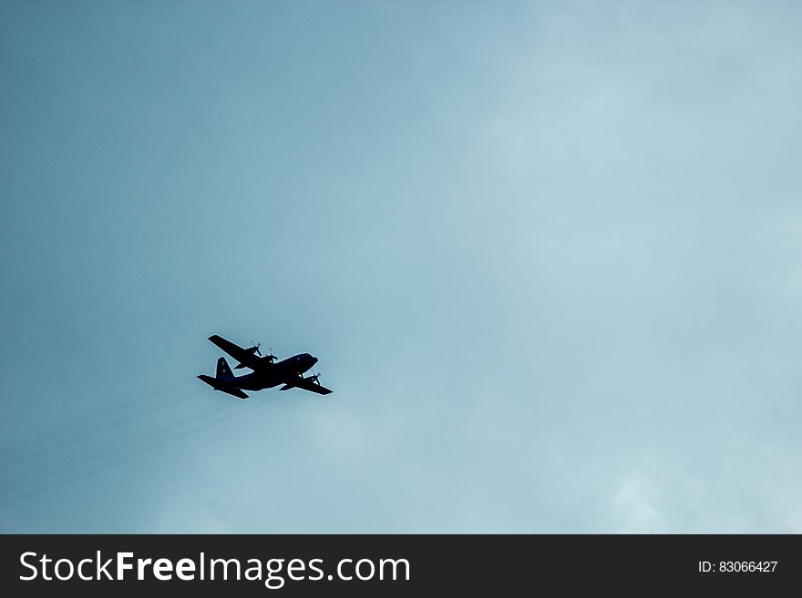 Airplane Against Blue Cloudy Sky Overhead