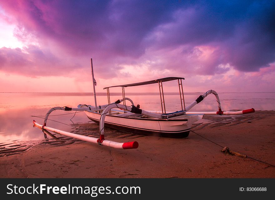 White and Black Motor Boar on Shore at Sunset