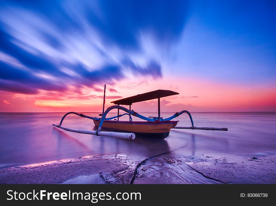 Brown Blue And White Wooden Boat During Orange Sunset