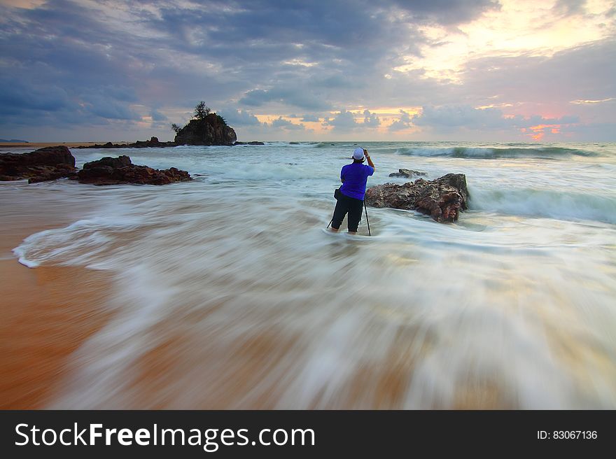 A casually dressed man standing in shallow water on a sandy beach. A casually dressed man standing in shallow water on a sandy beach.