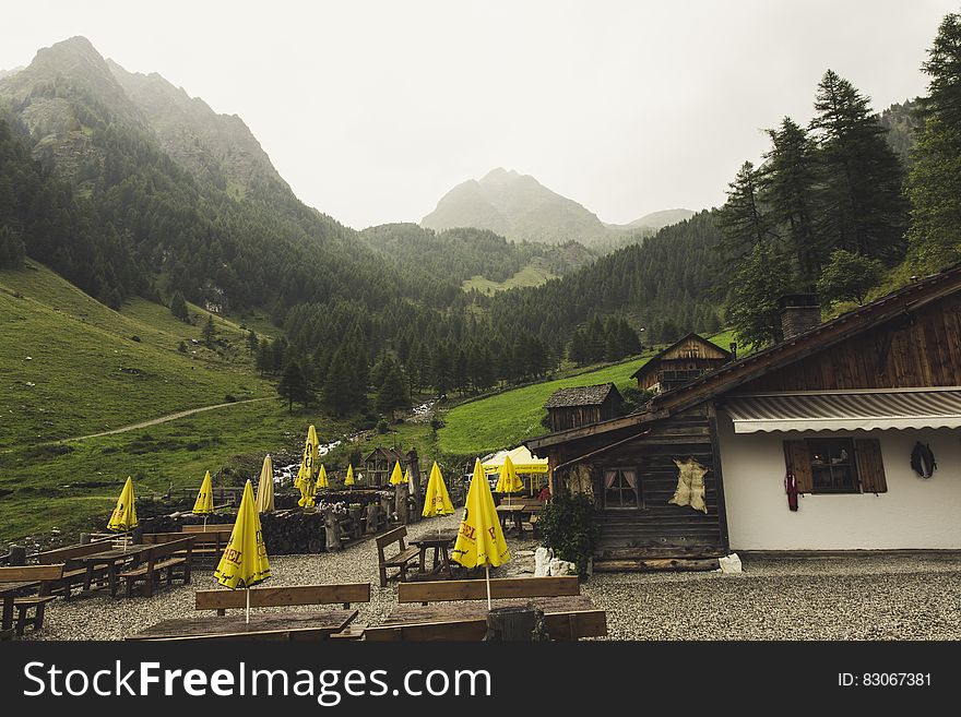 Cafe building with outdoor table and parasols in valley with mountains in background. Cafe building with outdoor table and parasols in valley with mountains in background.
