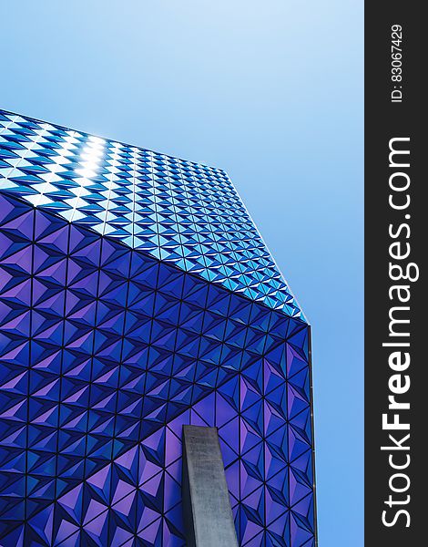 Exterior of geometric patterned blue building with sky background.