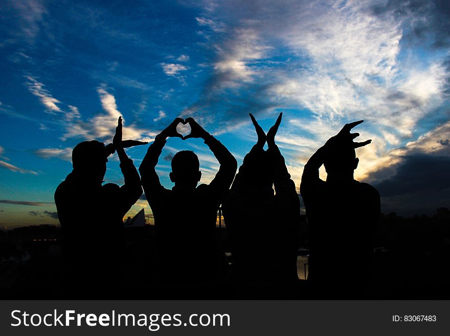 A group of people forming the word "LOVE" with their hands at sunset. A group of people forming the word "LOVE" with their hands at sunset.