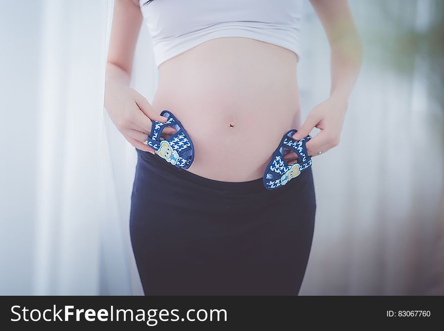 Pregnant Woman Holding Baby Shoes in Her Tummy