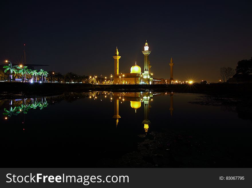 Reflection of Yellow High Rise Tower during Night Time