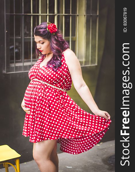 Woman in Red and White Polka Dots Mini Dress Holding Her Stomach