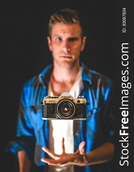 Portrait of man in blue shirt appearing to levitate Canon camera. Portrait of man in blue shirt appearing to levitate Canon camera.