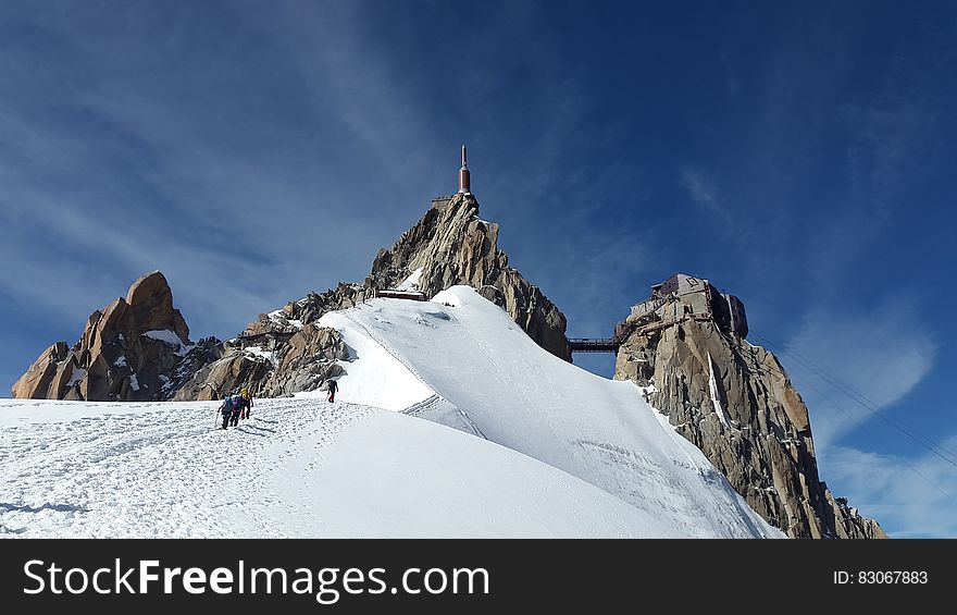 People Walking Toward Top of Mountain on Snow Covered Ground during Daytime