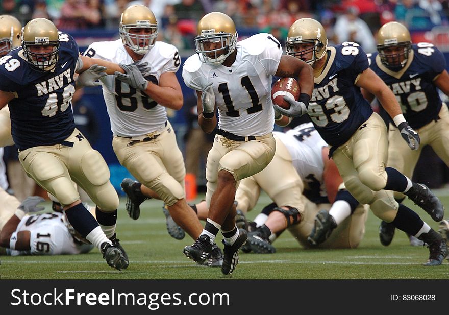 Group of Male Football Players Running on Field during Day