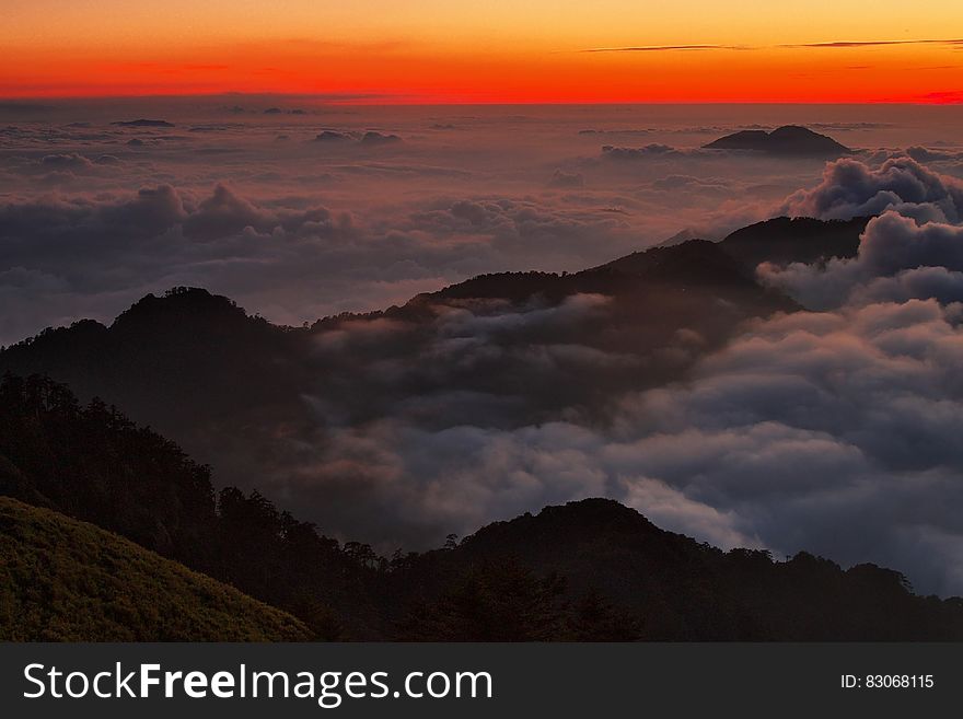 High View Photography Of Mountain Ranges Surrounded With Clouds At Golden Hour