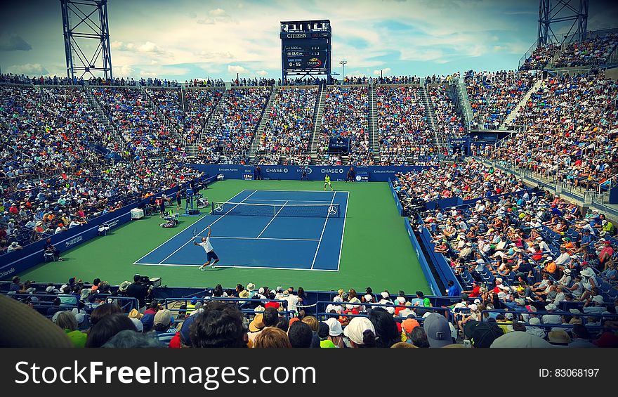 People Sitting On Bench Watching Tennis Event On Field During Daytime