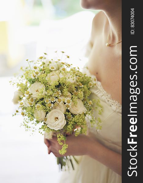 Woman in Bridal Gown Holding Bouquet of White Flowers
