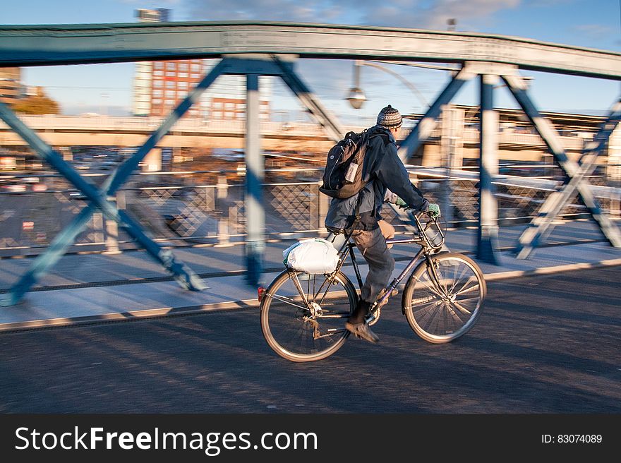 Man in Black Jacket Riding Black Bicycle in Gray Concrete Road in Panning Photography