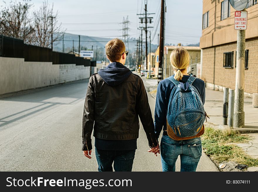 Man and Woman Holding Hands While Walking