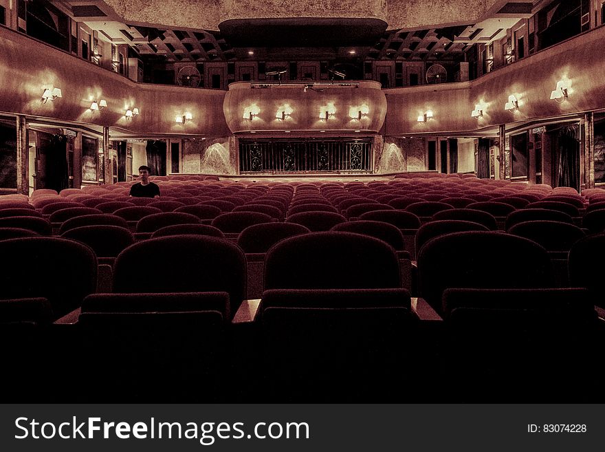 Person sitting inside opulent empty theater. Person sitting inside opulent empty theater.