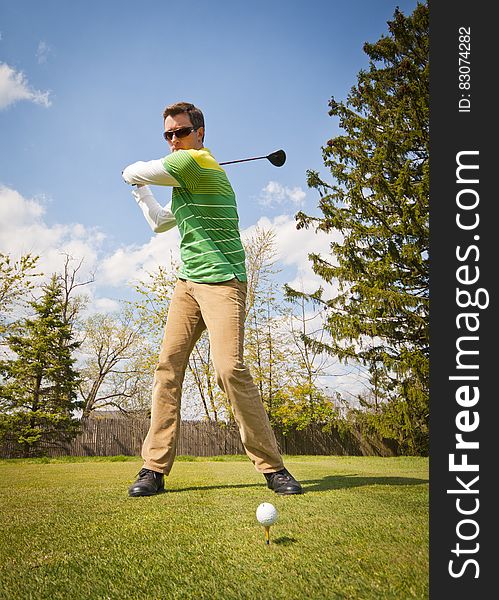 Man in Green and White Stripes Long Sleeve Shirt Holding Black Golf Club