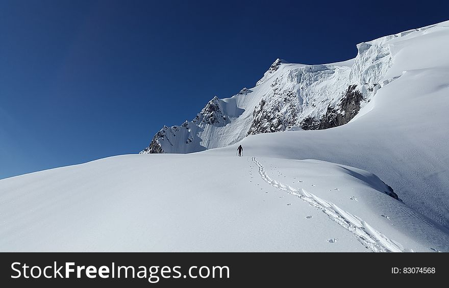 Man Walking in White Mountain Snow during Daytime