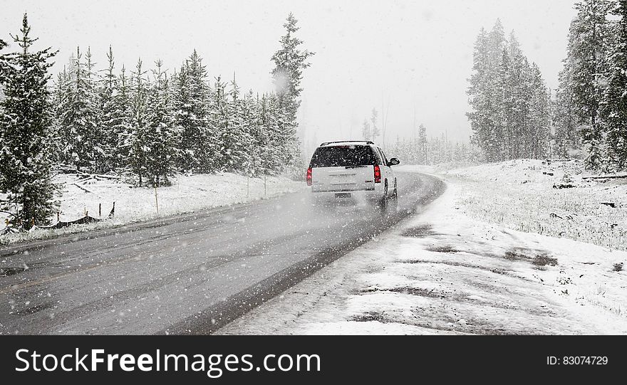 A car passing on the road with snow falling in the winter. A car passing on the road with snow falling in the winter.