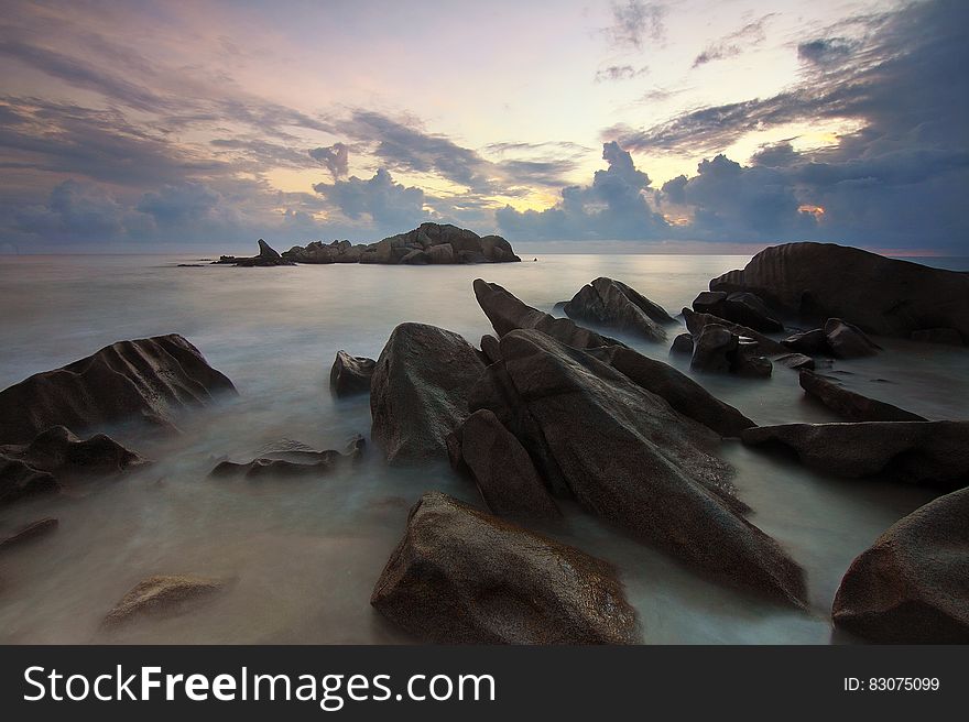 Blurs of water over rocks on sandy beach at sunset. Blurs of water over rocks on sandy beach at sunset.
