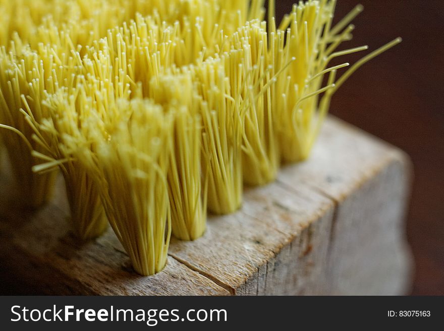 Close up of yellow bristles on wooden broom block. Close up of yellow bristles on wooden broom block.