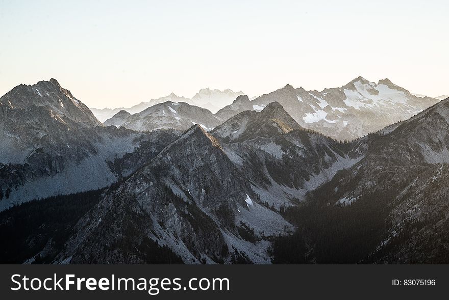 Mountain tops with snow and slopes leading down to narrow valleys, sky threatening more snow. . Mountain tops with snow and slopes leading down to narrow valleys, sky threatening more snow. .