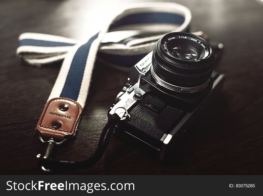 Vintage Olympus camera with cloth strap on desktop.