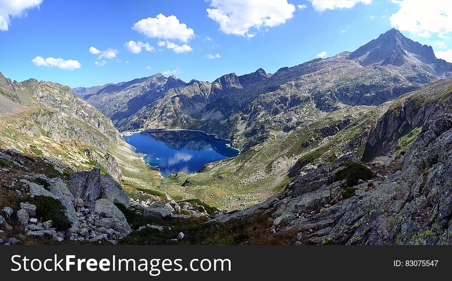 Lake Surrounded by Mountain Top Under Blue Sky at Daytime