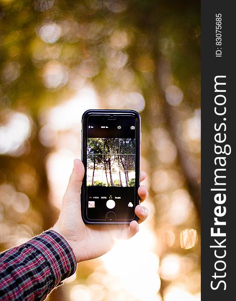 Hand holding smartphone with camera on touchscreen outdoors. Hand holding smartphone with camera on touchscreen outdoors.