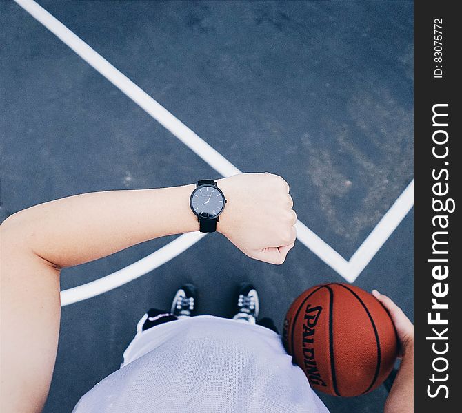 Person Wearing Black Round Analog Watch on Left Wrist While Holding Basketball on Right Hand