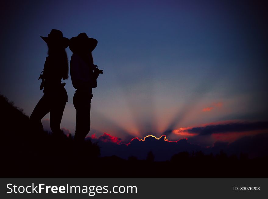Silhouettes of people standing on a hill at sunset. Silhouettes of people standing on a hill at sunset.