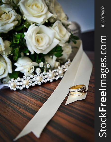 A wedding bouquet of white roses and gold rings. A wedding bouquet of white roses and gold rings.