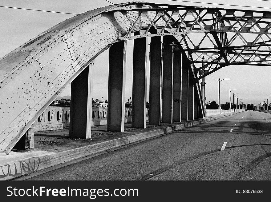 A black and white photo of a bridge with an arched metal structure. A black and white photo of a bridge with an arched metal structure.