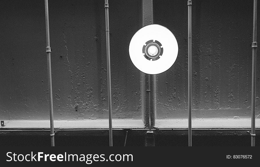 Underside black and white view of light handing from industrial building ceiling. Underside black and white view of light handing from industrial building ceiling.