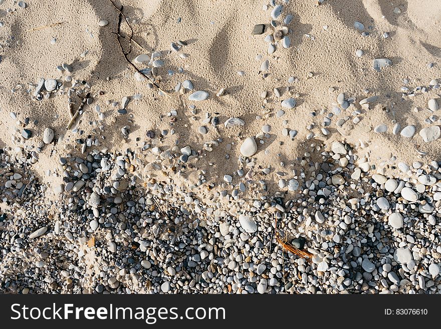 A close up of a beach with sand and pebbles. A close up of a beach with sand and pebbles.