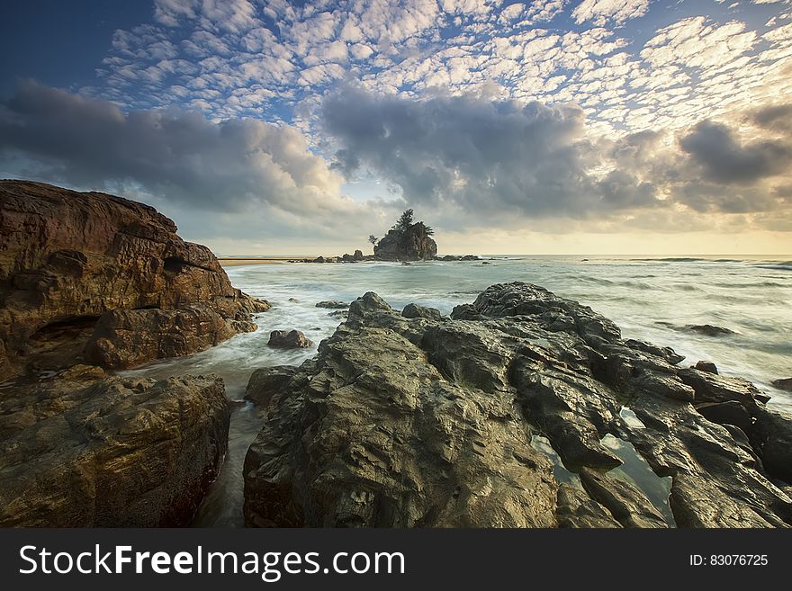 Brown Rocks on Seashore Under White Cloud Sky