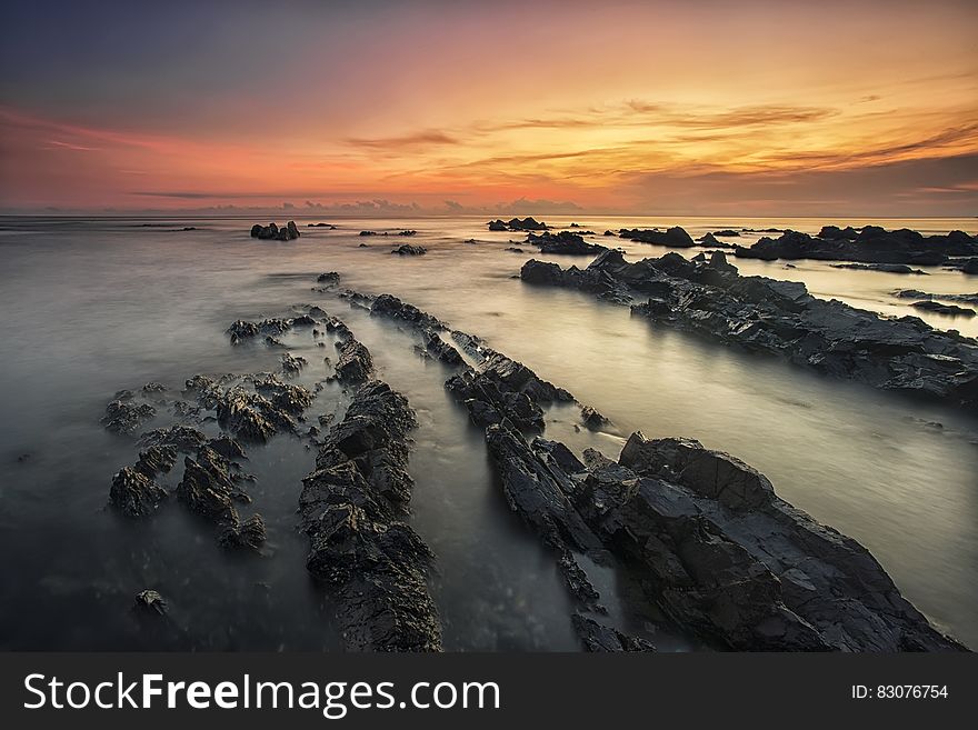A rocky beach and colorful sky at sunset. A rocky beach and colorful sky at sunset.