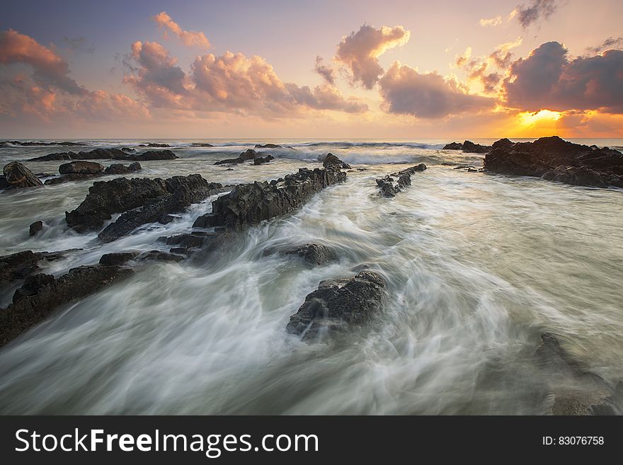 Pink Cloudy Sunset over Rocky Ocean