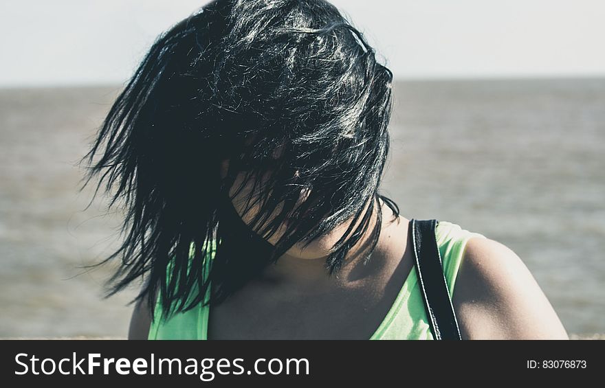 A portrait of a woman standing in the wind with hair over her face, open sea in the background. A portrait of a woman standing in the wind with hair over her face, open sea in the background.