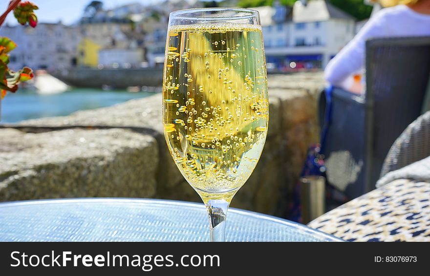 Clear Champagne Glass With Yellow Liquid on Blue Glass Round Table